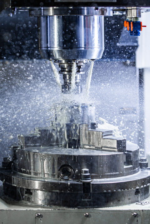 Vertical photo of industrial wet milling process in 5-axis cnc machine with coolant flow u