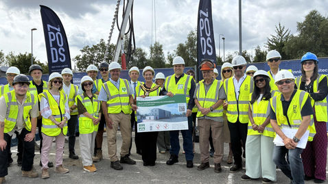 The ZED PODS and Tonbridge and Malling Borough Council teams in high-visibility jackets and hard hats, standing together in front of a crane at the Blue Bell Hill construction site as work begins on 12 modular homes.