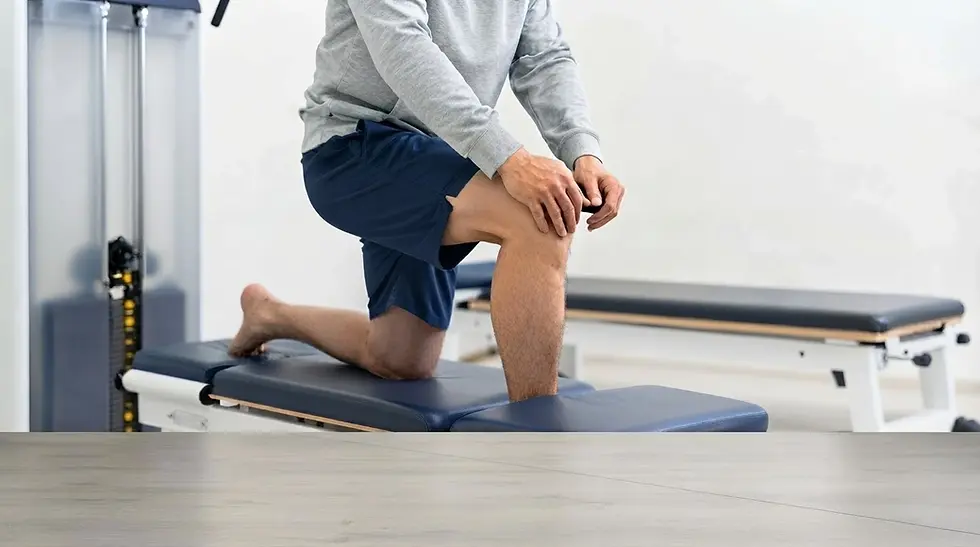 Studio photography of a person performing a kneeling stretch on a physical therapy table. The scene is clinical and professional, emphasizing rehabilitation or fitness recovery.