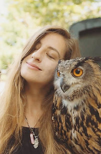 A calm woman closing her eyes next to an old owl.