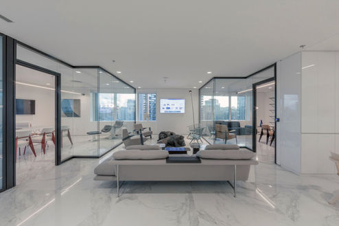 Modern office waiting room with multiple seating areas and glass partitions.