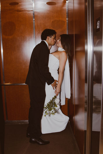 Newlywed couple kissing in a wood-paneled elevator