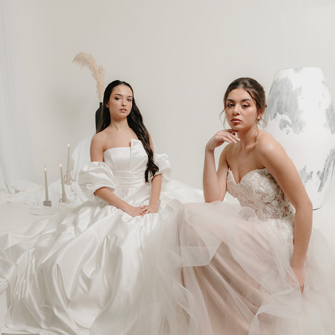 Dans un décord au ton blanc on y voie 2 mariées assise en robe de mariée