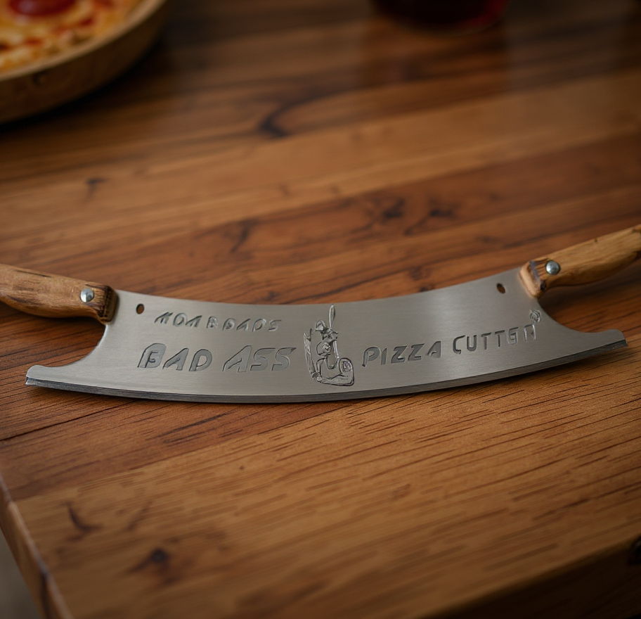 Mezzaluna pizza cutter with "BAD ASS PIZZA CUTTER" text on wood.