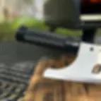 Black-handled pizza rocker knife resting on a wooden board outdoors.