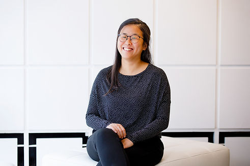 Coach Esther Hur sitzt vor einem weißen Hintergrund und lacht in die Kamera