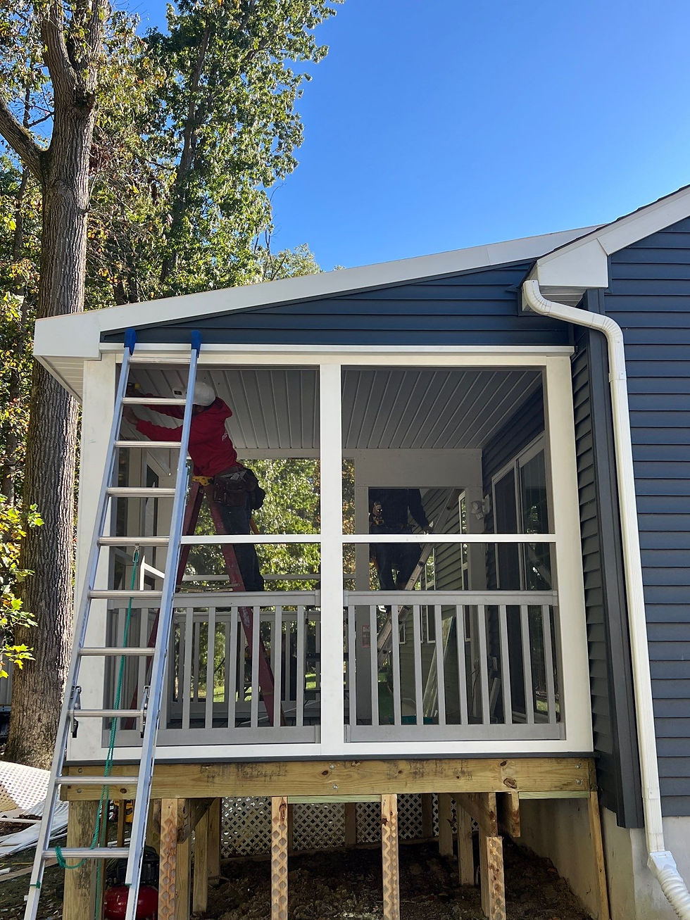 Construction worker on ladder repairing porch, blue siding, clear sky, roofing contractor.