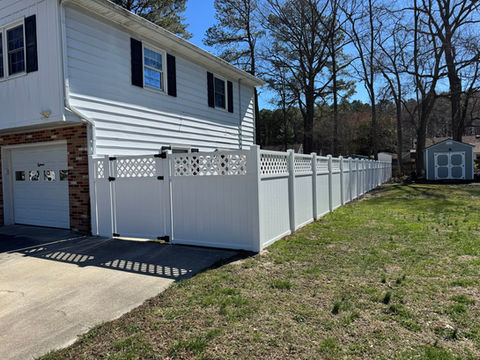 White fence surrounding a residential home and yard, with a shed.