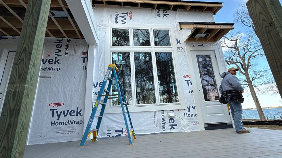 Construction worker standing near house with Tyvek HomeWrap siding replacement, outdoors.