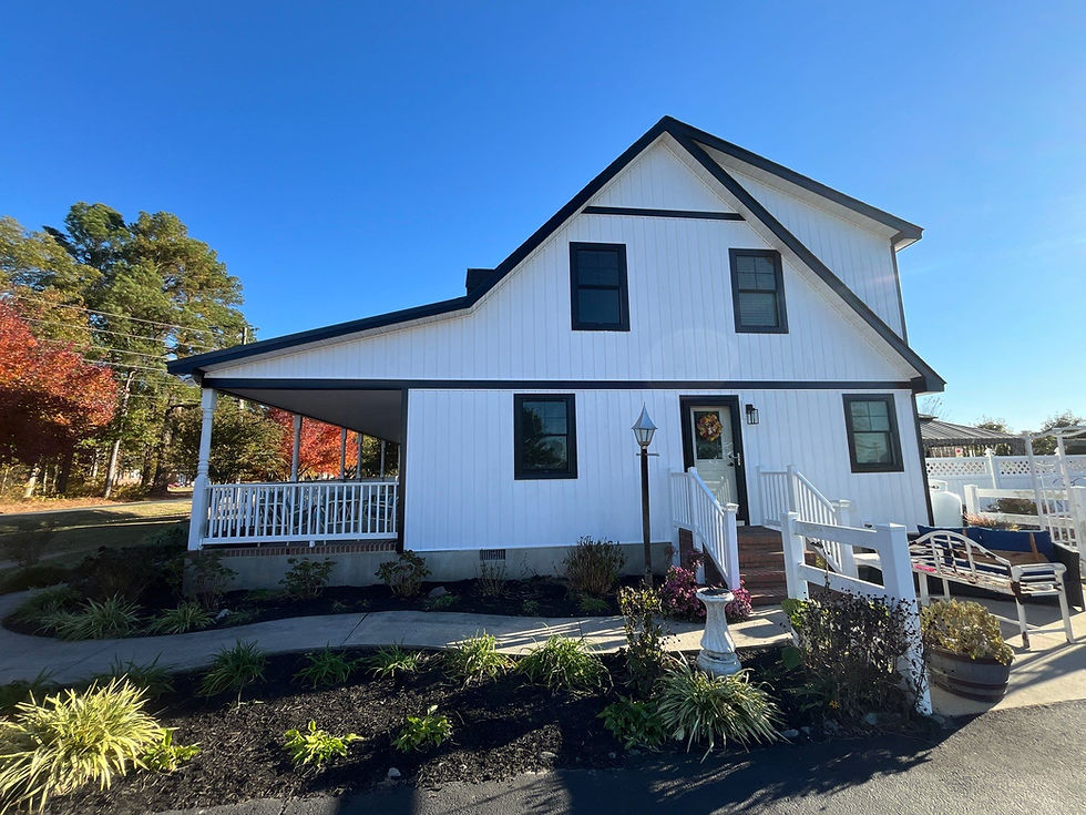 White house with black trim under a clear blue sky. Roofing Contractor