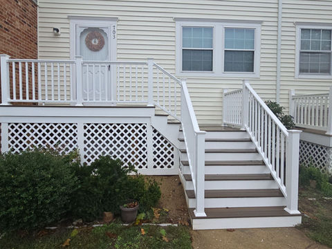 White deck and stairs leading to a house with a front door.