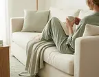 Woman relaxing on a cozy sofa, holding a mug in her living room.