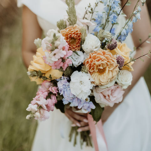 Private property wedding Mackay photographer close up of bride holding a colour bouquet consisting of warm tone roses and dahlias 