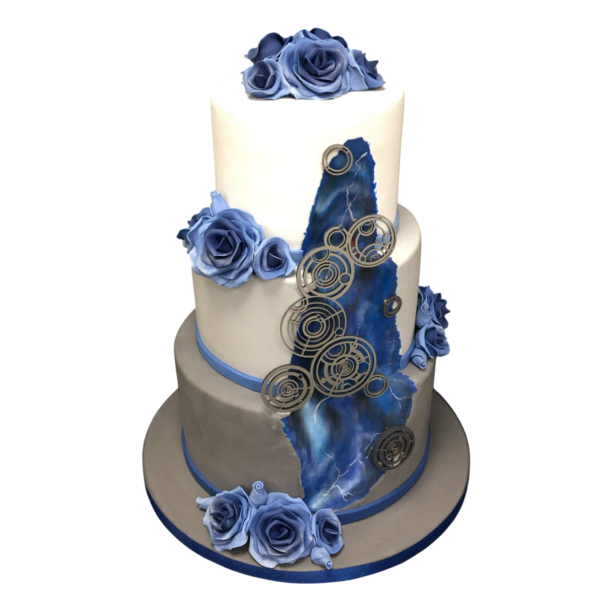 Three-tiered wedding cake with blue sugar paste roses and metallic accents.