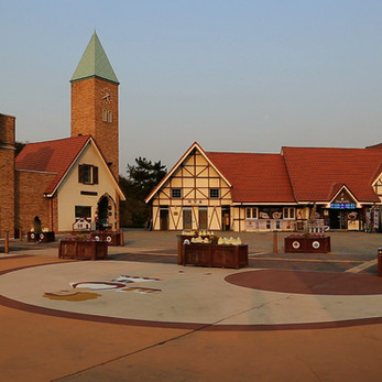 German-style village square showcasing half-timbered buildings, an archway, and prominent tower.