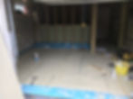 Empty room with timber stud walls and blue waterproof edging around the floor