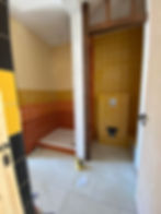 Tiled wall and floor in a finished WC room beside a timber door