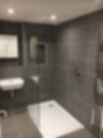 Finished shower room with frameless glass screen, low-profile tray and grey tiles