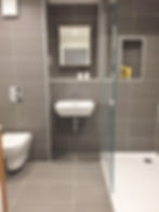 Shower room with wall-hung WC, small basin and grey tiled walls