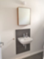 Wall-mounted basin and mirror on a grey tiled wall