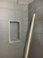 Recessed shower niche in grey large-format wall tiles