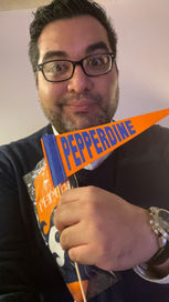 Leyder "Aiden" Murillo smiling with a Pepperdine pennant and Waves socks, won at the 'Mile High' Waves Alumni Group event in Denver.
