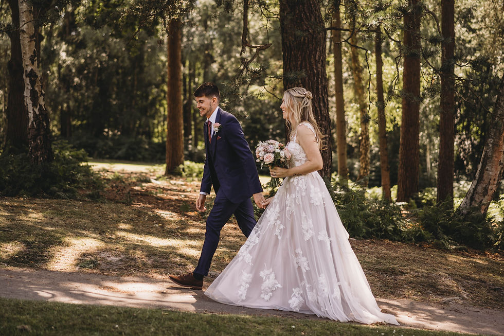 bride and groom walking through woodland at Cottesmore wedding venue in sussex