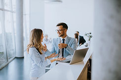 young-business-couple-working-discussing-by-laptop-office-front-their-team.jpg