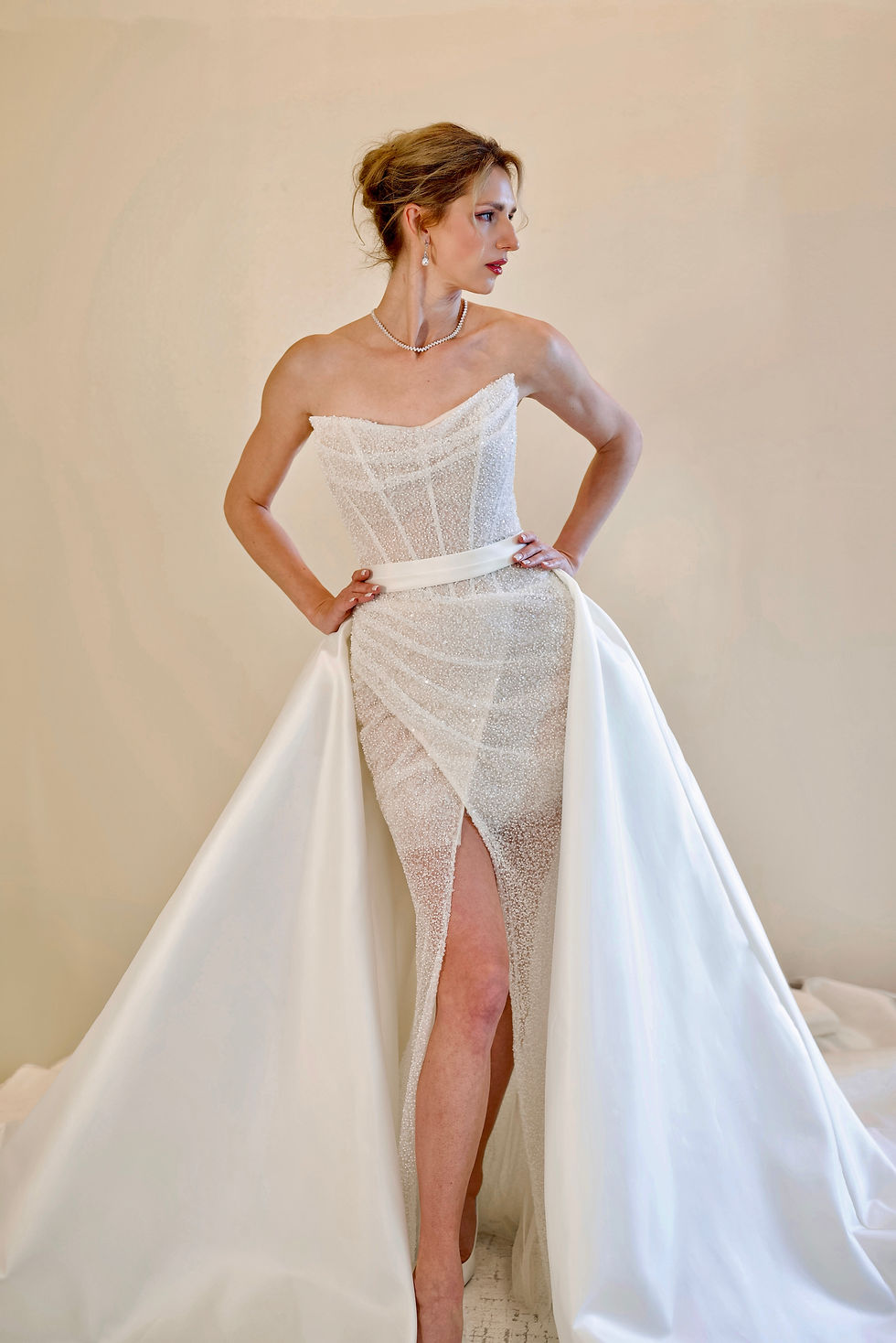 Beaded corset bridal gown with slit and detachable satin overskirt.