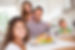 Family smiling at the camera at dinner t