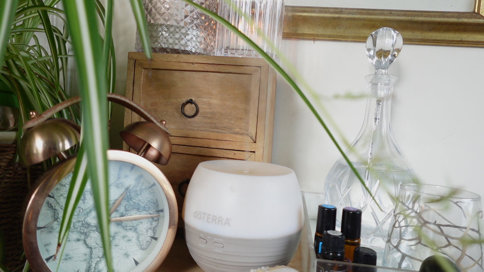 Essential oils, a clock and a plant with long leaves in the room of a complementary therapist on the Essex, Hertfordshire border