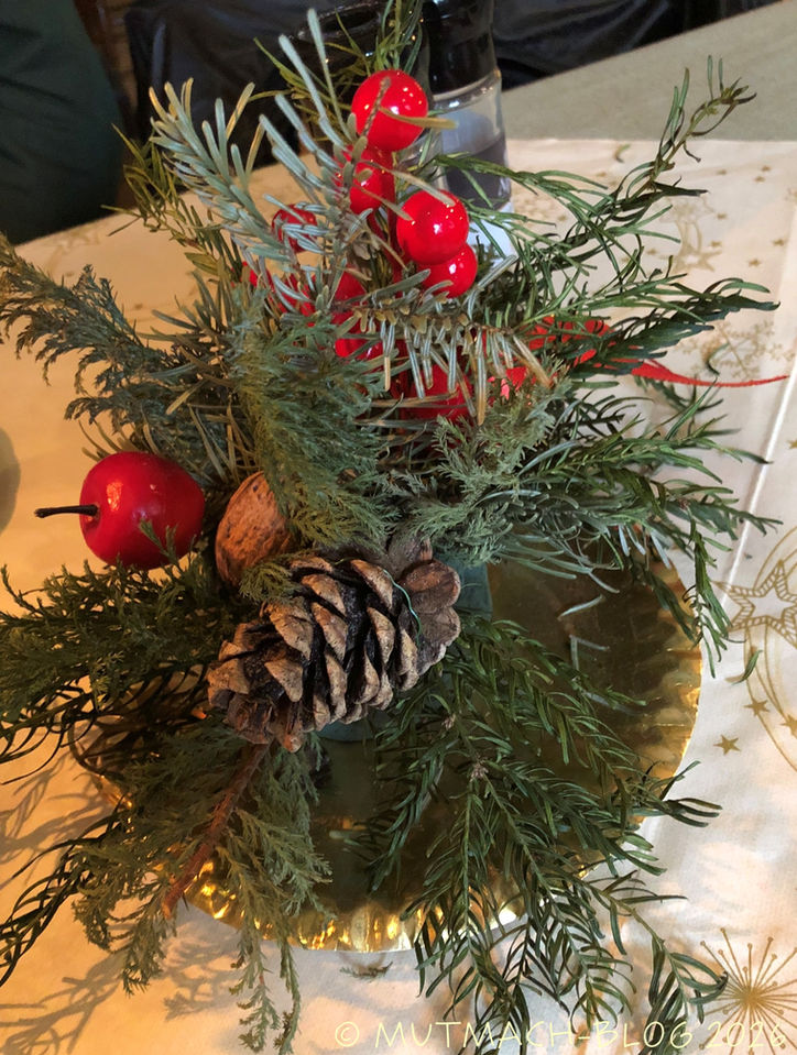 Weihnachtliche Tischdekoration mit Tannenzweigen und Zapfen.