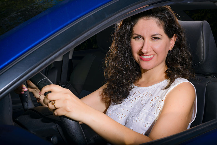Mujer sonriendo conduciendo un coche azul