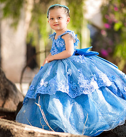 Adorable niña en vestido azul posa para foto al aire libre.
