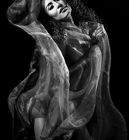 Una mujer baila con tela translúcida, retrato en blanco y negro, elegante.