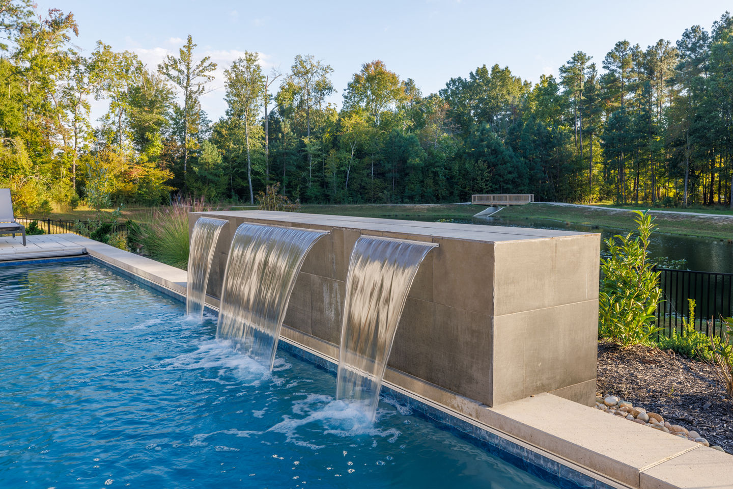 a waterfall in a swimming pool with trees in the background