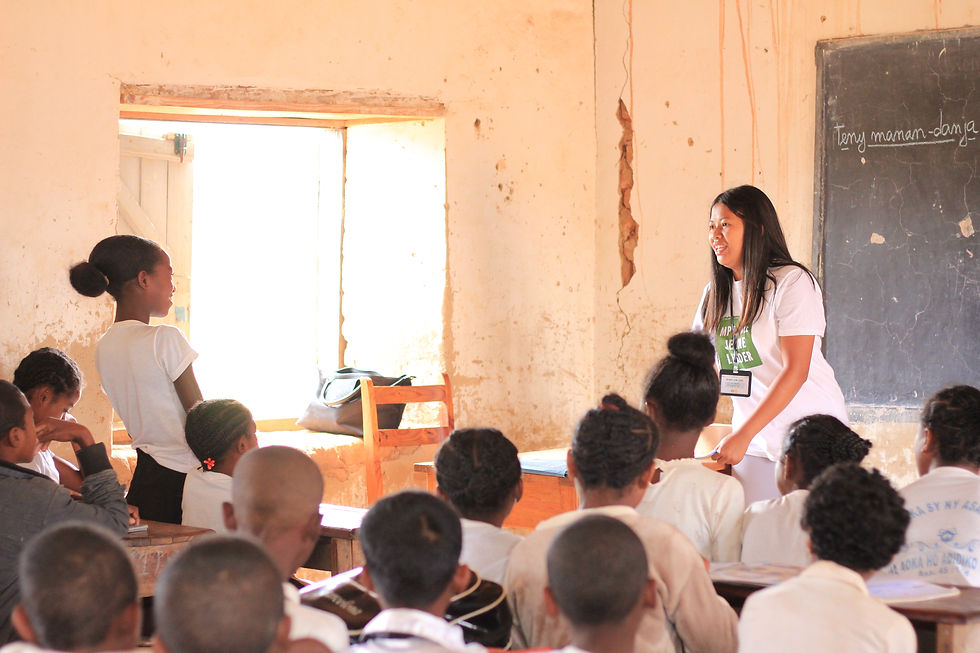 A teacher-trainee, now also a comprehensive sexuality educator with Projet Jeune Leader, teaching a class at Soaindana middle school in rural Madagascar. She is speaking to a female student in the classroom.