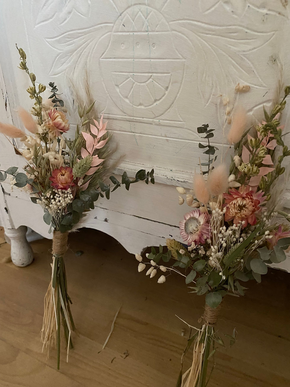 Floral posies standing against a white piece of furniture