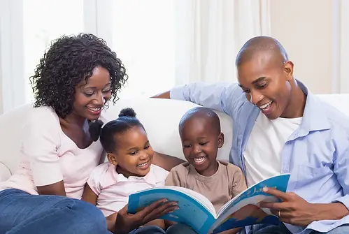 Happy family on the couch reading storybook at home in the living room-1.webp