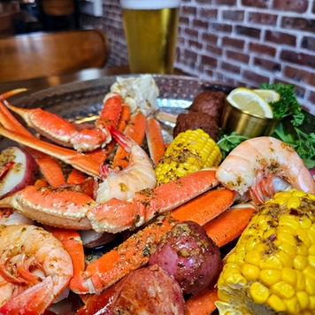 Large platter of Low Country Boil with crab legs, shrimp, red potatoes, corn, and hush puppies