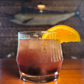 Old Fashioned cocktail in a historic brick building with large Marlin on the wall