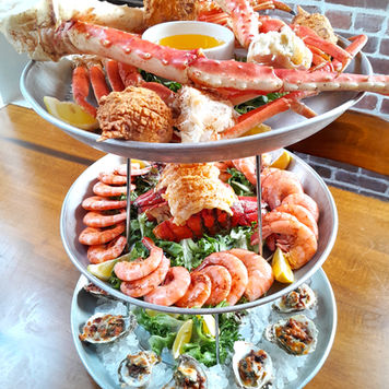 A huge, 3 tier tower of oysters, shrimp, crab legs, and lobster tail