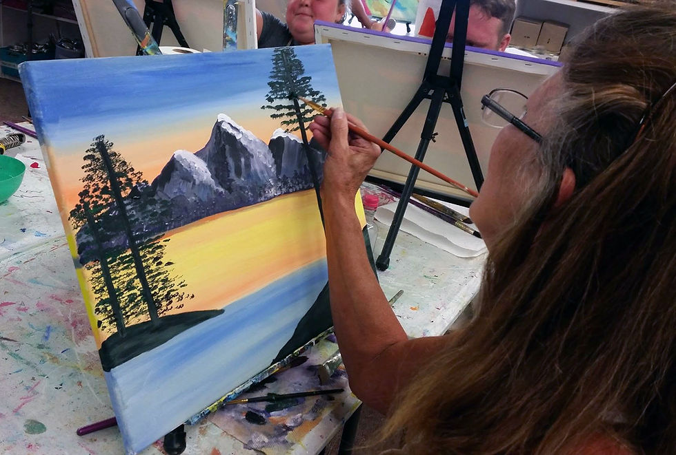 Woman painting a mountain landscape at an adult art class