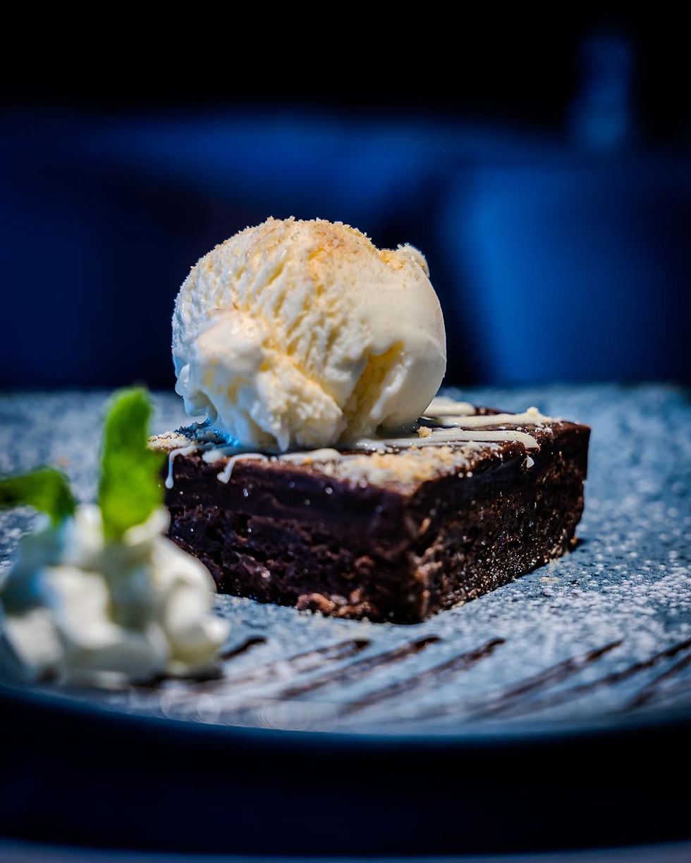 Gluten Free Brownie with ice cream served on a plate at Molti Restaurant.