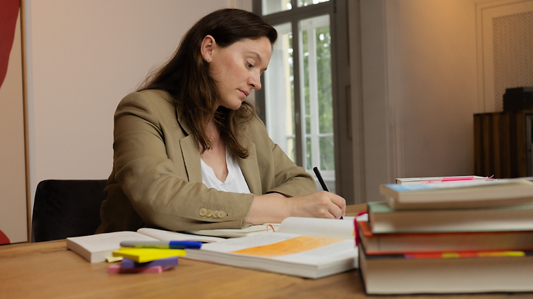 Jutta Kallies-Schweiger schreibend am Tisch soluvaire.png