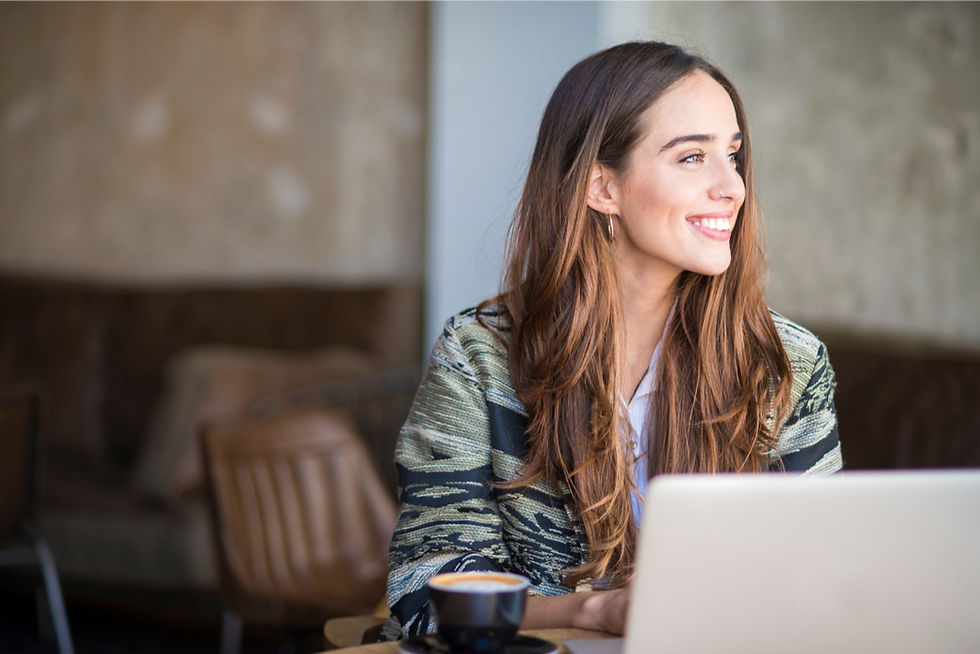 A person sitting at a desk using a laptop computer and smiling.