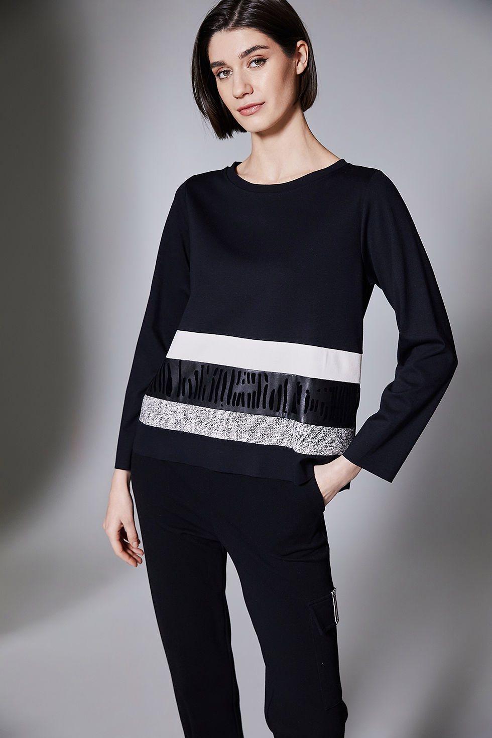 Model posing with hand in pocket wearing Peruzzi Multi Stripe Top – stylish side angle.