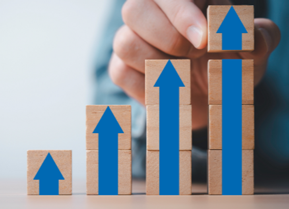 Businessman stacking arrow on the top of wooden block for business growth and achievement