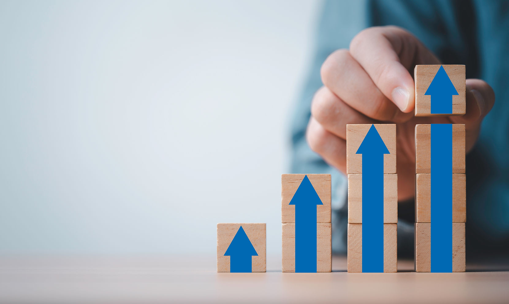 Businessman stacking arrow on the top of wooden block for business growth and achievement