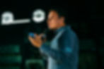 A man in a denim jacket holds a microphone